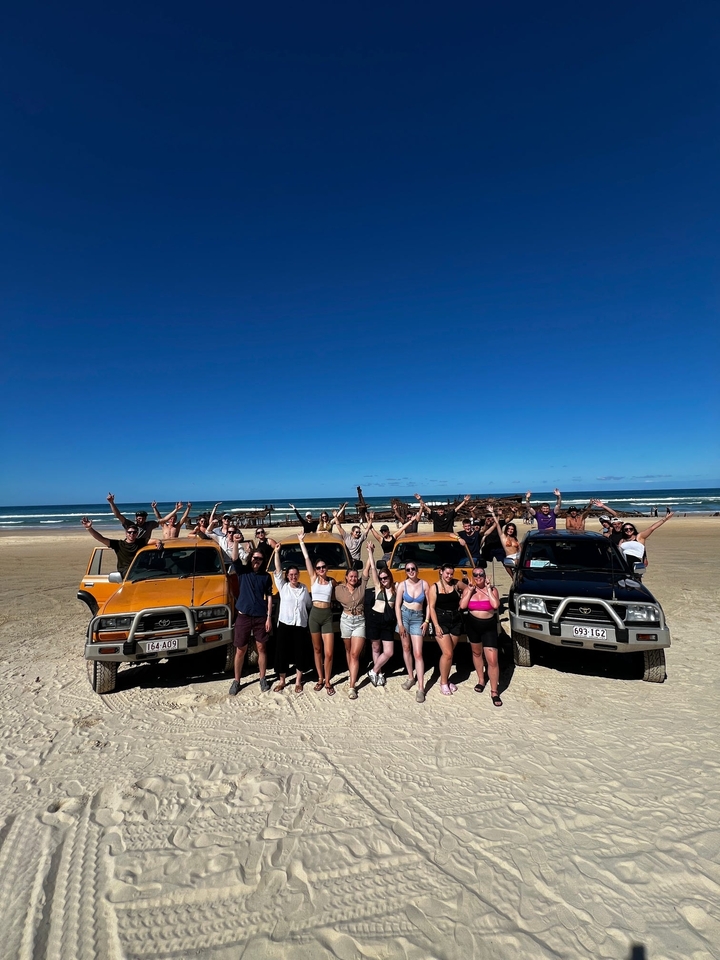 Groupe posant avec des véhicules 4x4 sur une plage