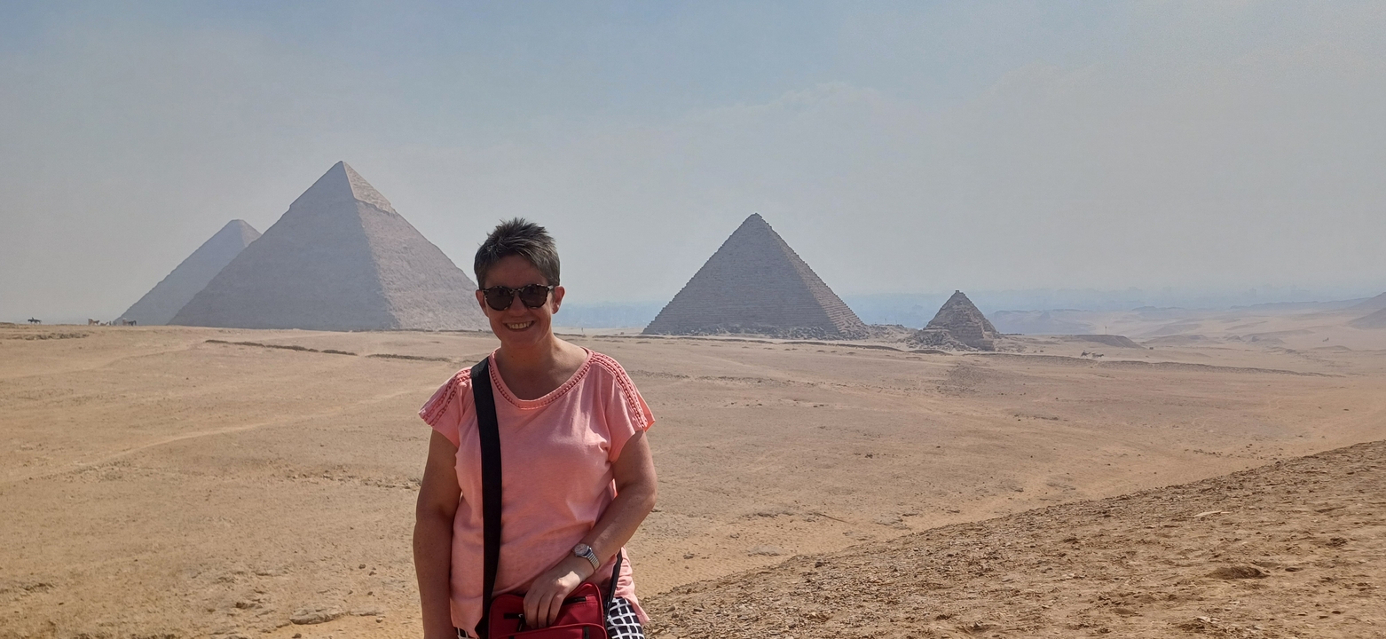 Une personne debout avec les pyramides en arrière-plan.