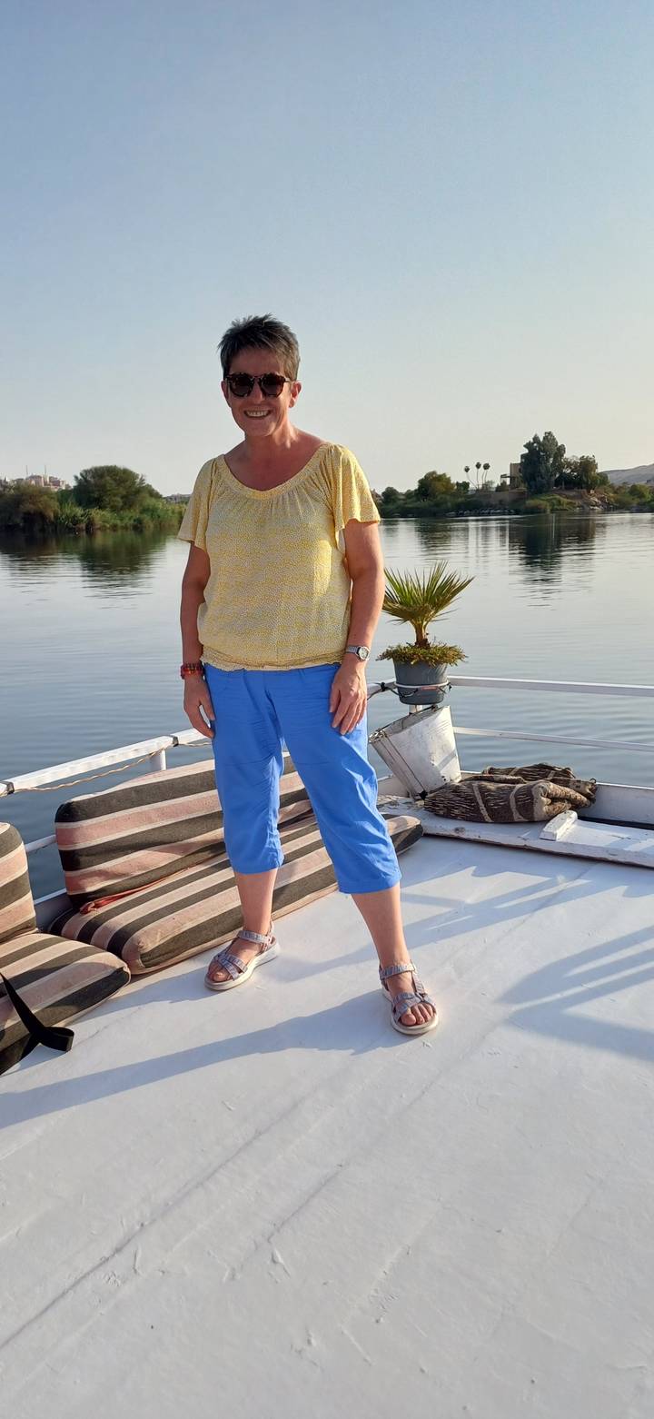 Femme posant sur un bateau près de l'eau.