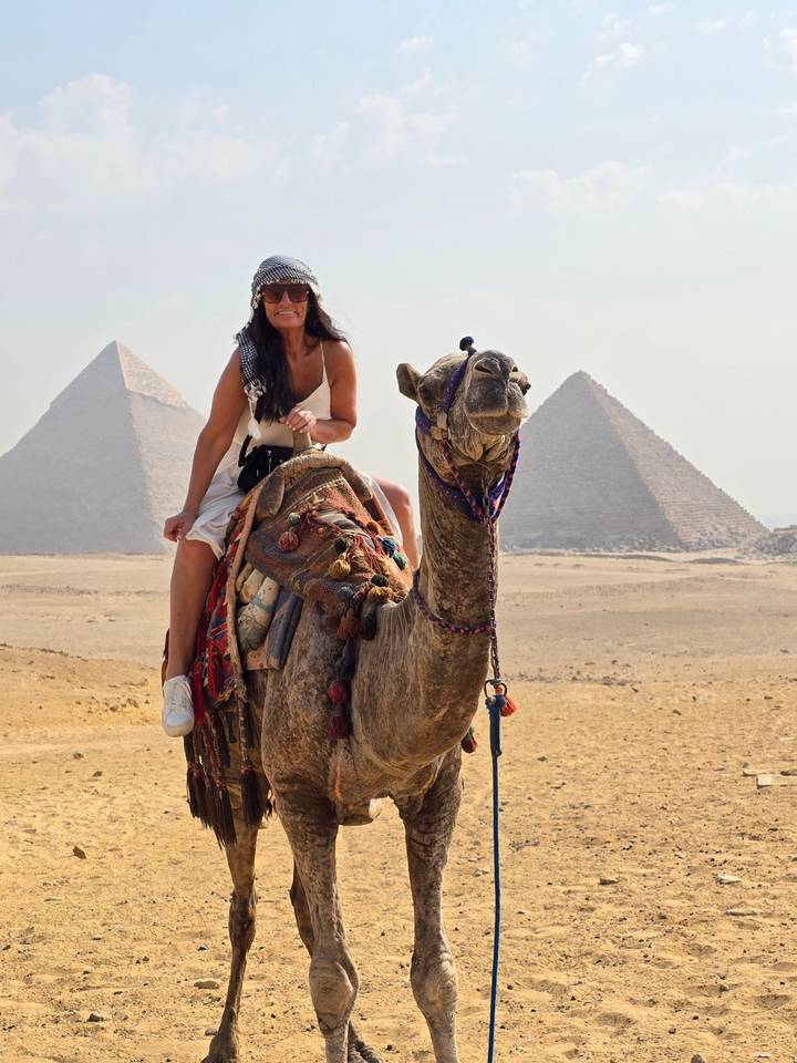 Femme montant un chameau près des pyramides.