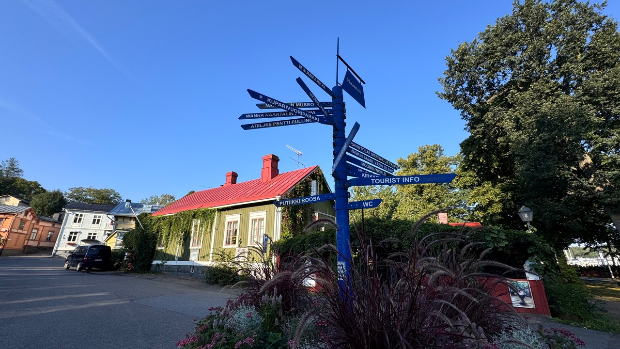 Un panneau de rue avec plusieurs directions touristiques dans une ville pittoresque.