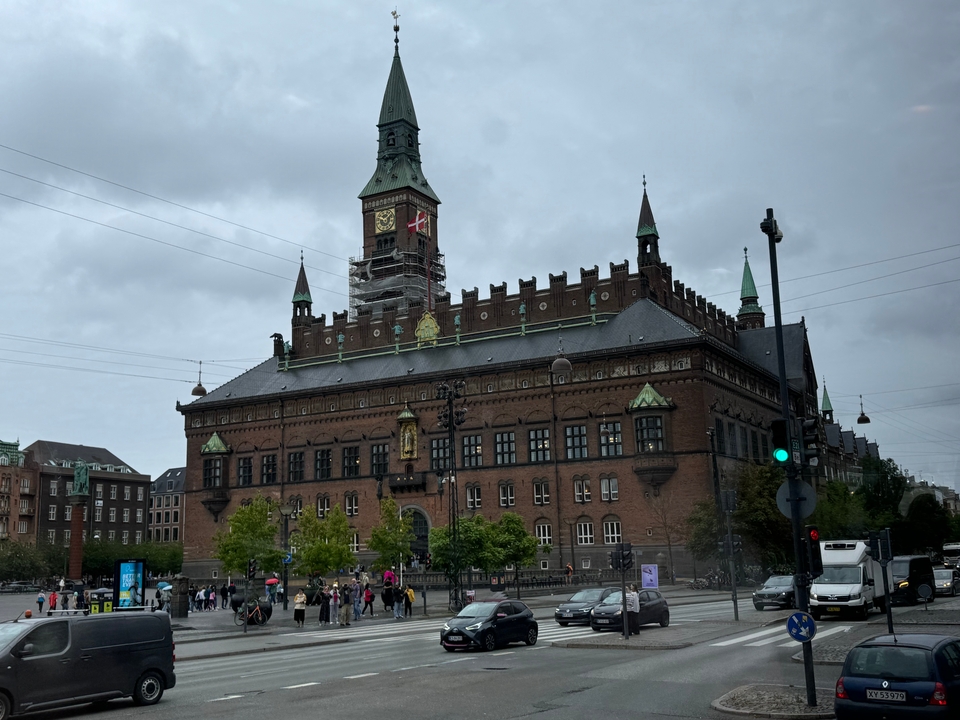 Grande mairie avec tour d'horloge et piétons.