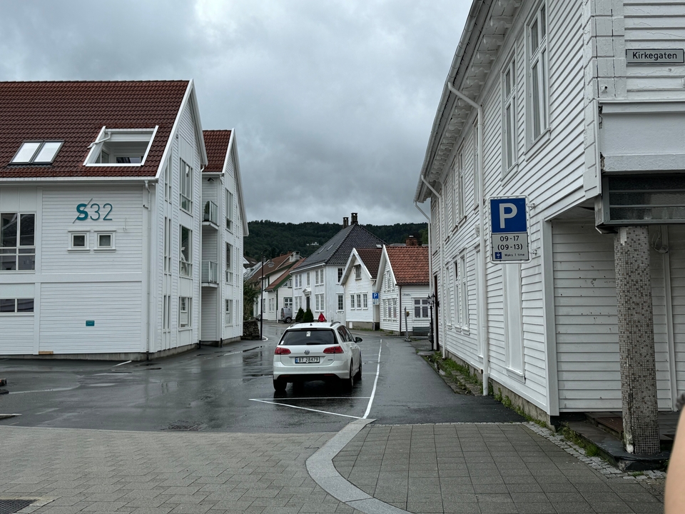 Une vue de rue avec des maisons en bois blanc et des voitures garées.