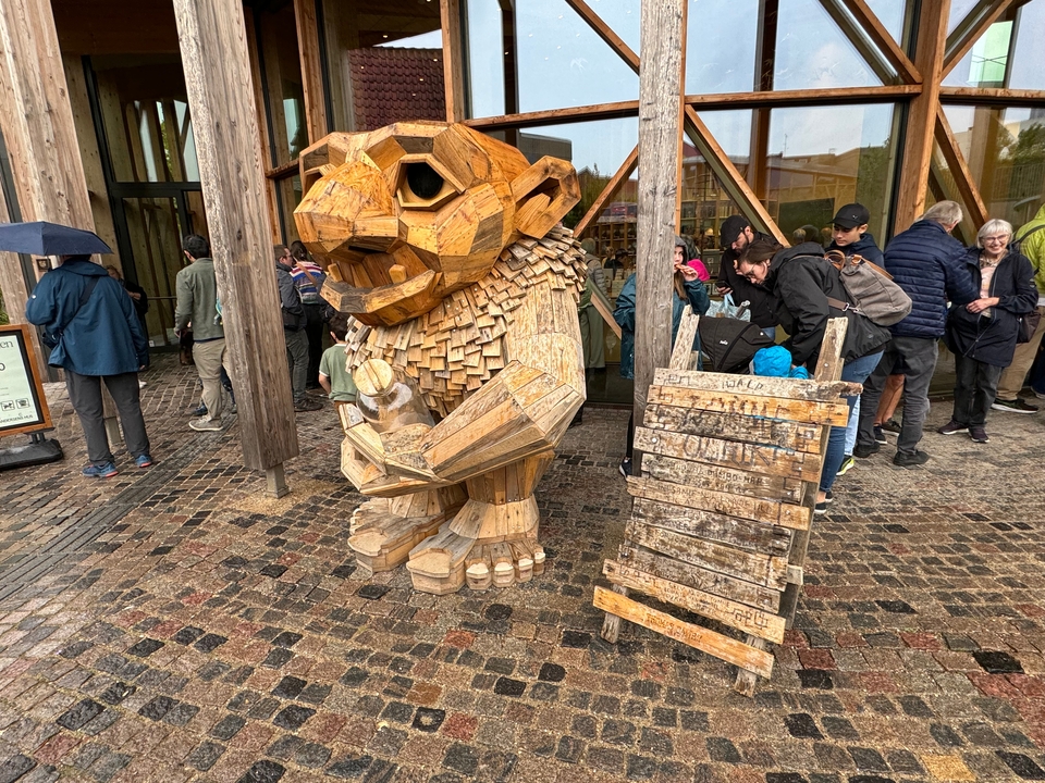 Une sculpture en bois avec un groupe de personnes qui observent.
