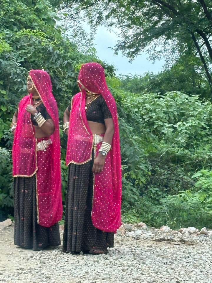 Deux femmes en vêtements traditionnels dans un cadre verdoyant.