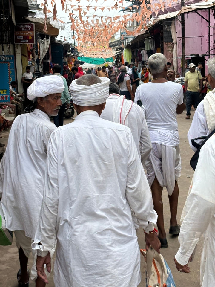Groupe de personnes en tenue traditionnelle blanche qui marchent.