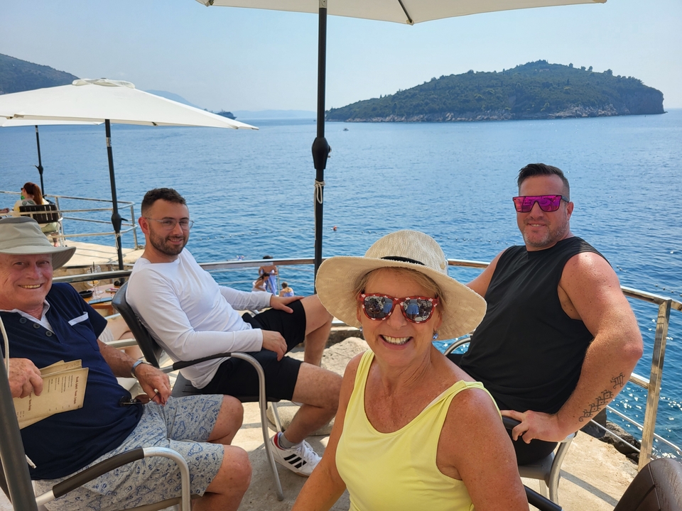Groupe de personnes dans un café en bord de mer avec vue sur l'océan.
