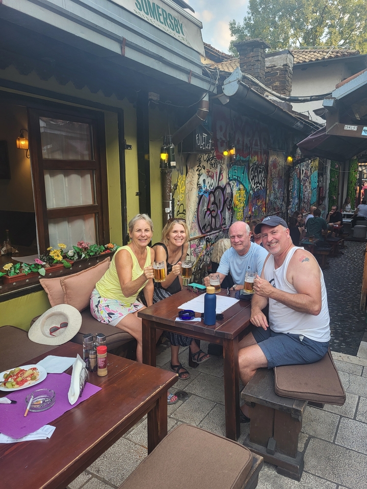 Quatre personnes savourant des boissons dans un café en plein air avec des graffitis sur les murs.