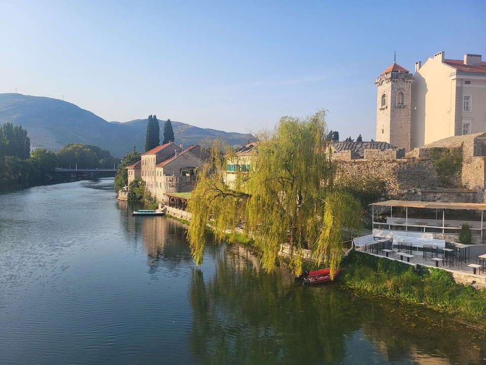 Une rivière avec des saules et des bâtiments historiques sur les rives.