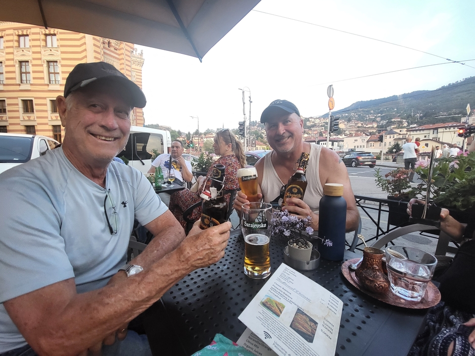 Deux personnes assises à un café en terrasse avec des boissons sur la table.