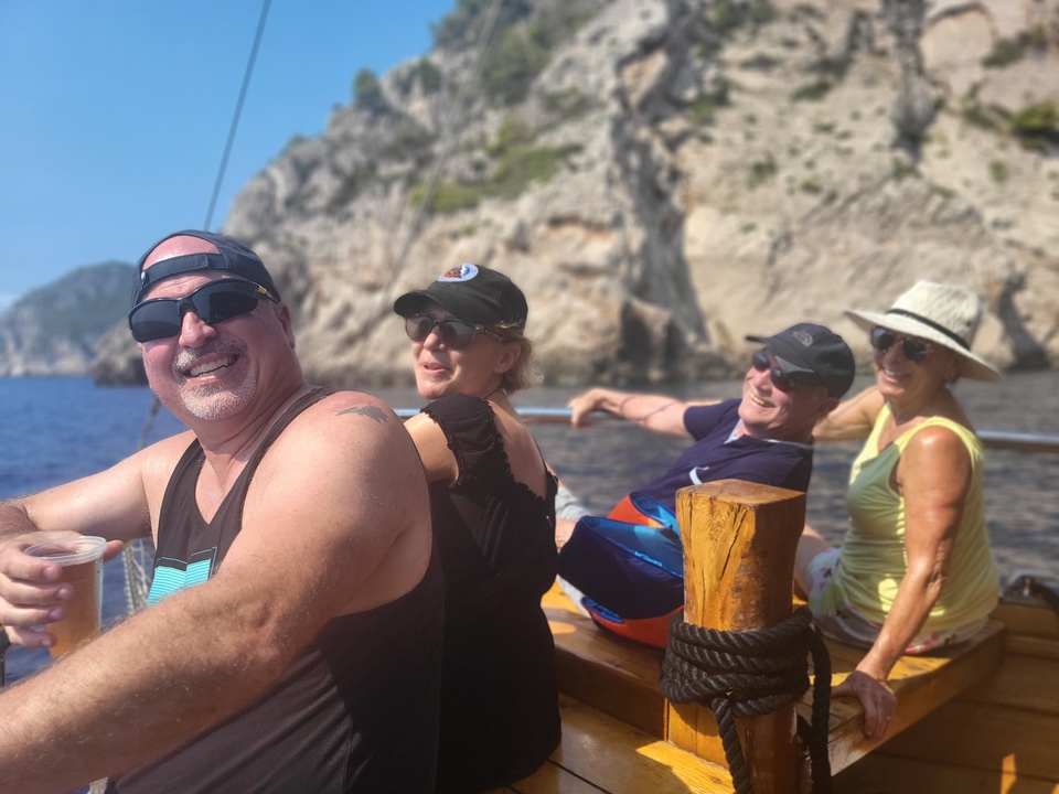 Groupe de quatre personnes sur un bateau avec des falaises rocheuses en arrière-plan.