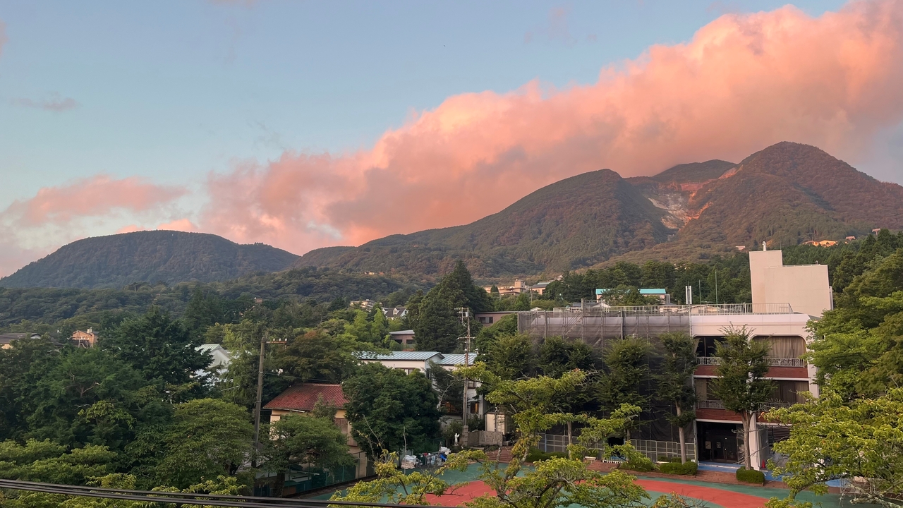 Coucher de soleil sur les montagnes avec de doux nuages roses dans le ciel.