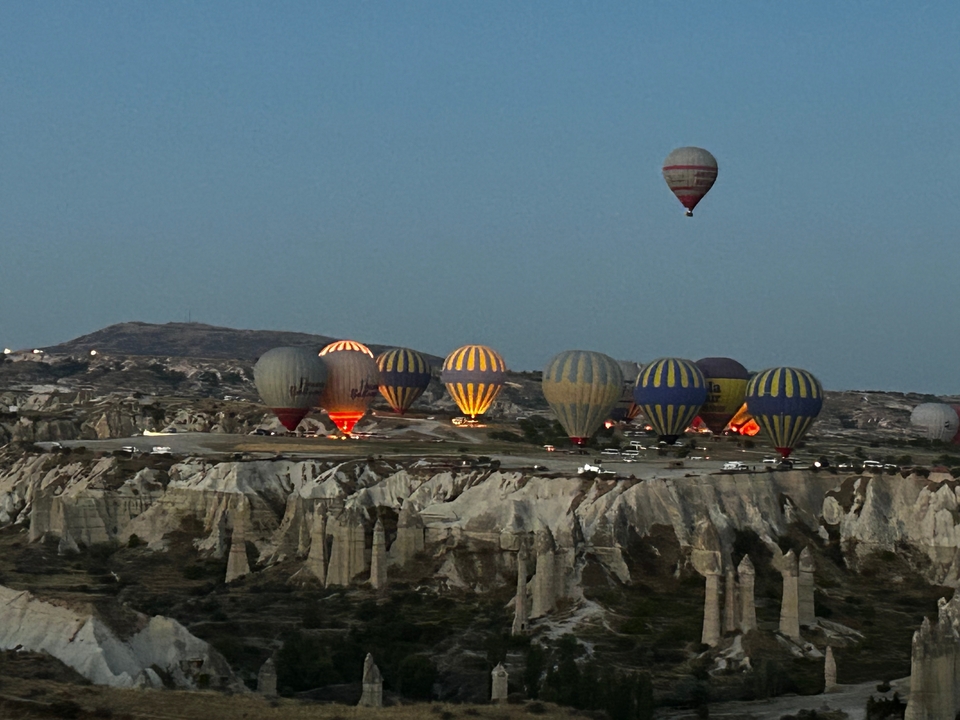 Hot air balloons rising over a rocky landscape at dusk.