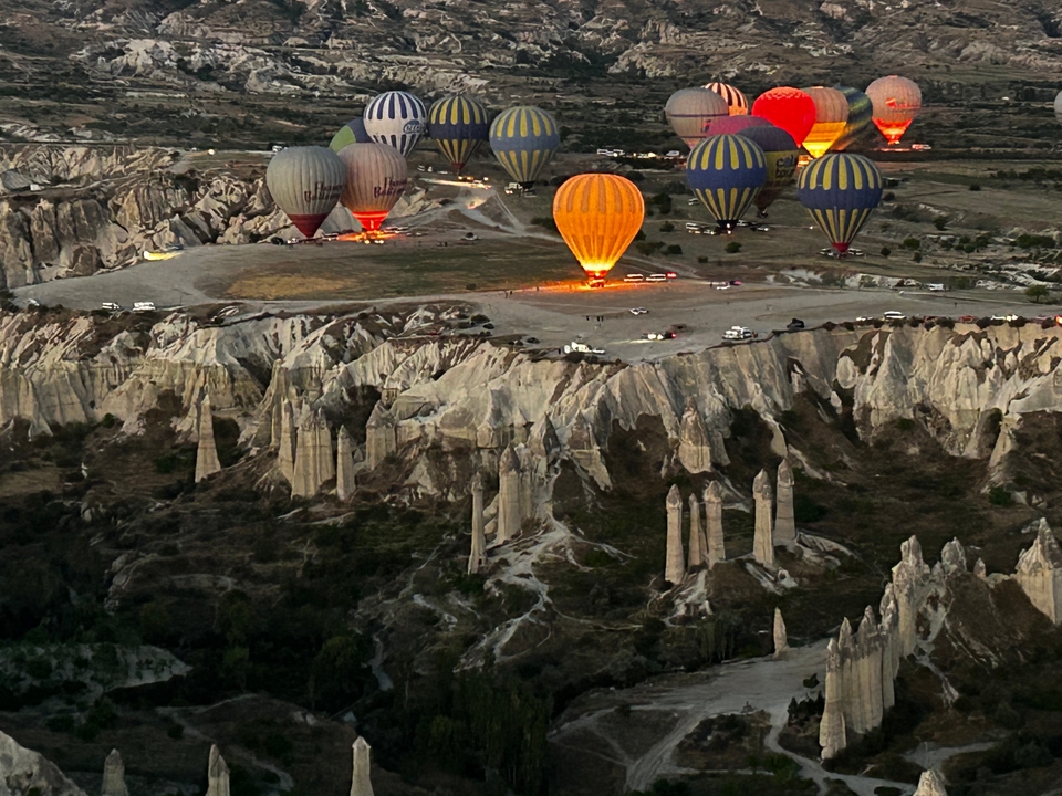 Colorful hot air balloons flying over a valley with unique rock formations.