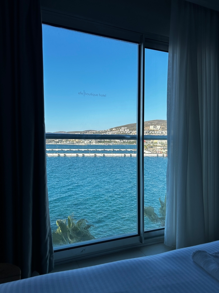 View from a hotel room window overlooking the sea and a harbor.
