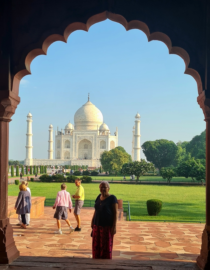 Le Taj Mahal vu de loin avec des jardins et des personnes.