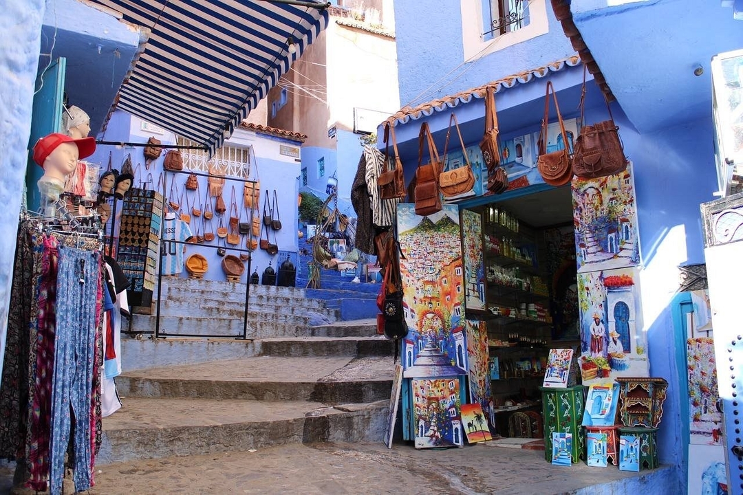 Rue colorée à Chefchaouen avec boutiques et escaliers.