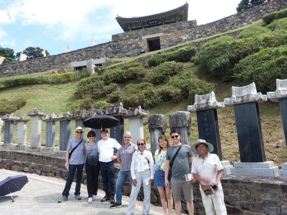 Un groupe posant devant des tablettes de pierre et un mur ancien.