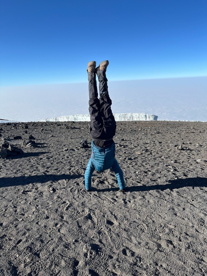 Personne faisant un appui tendu renversé dans un paysage rocheux avec des glaciers en arrière-plan.