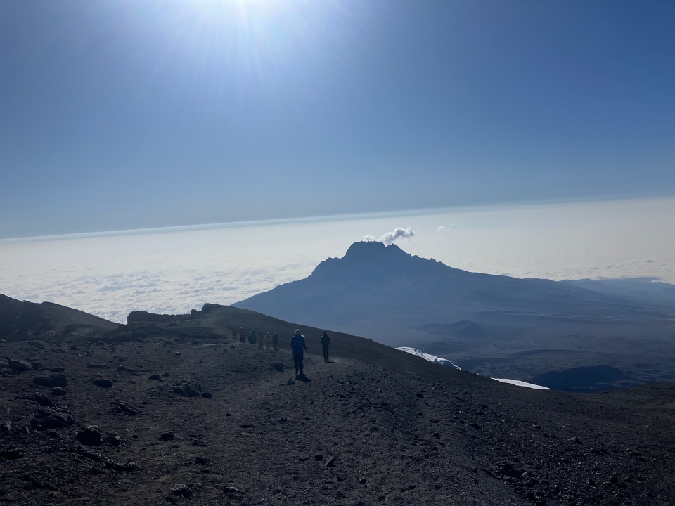 Des personnes qui font de la randonnée le long d'un sentier accidenté avec une montagne en arrière-plan.