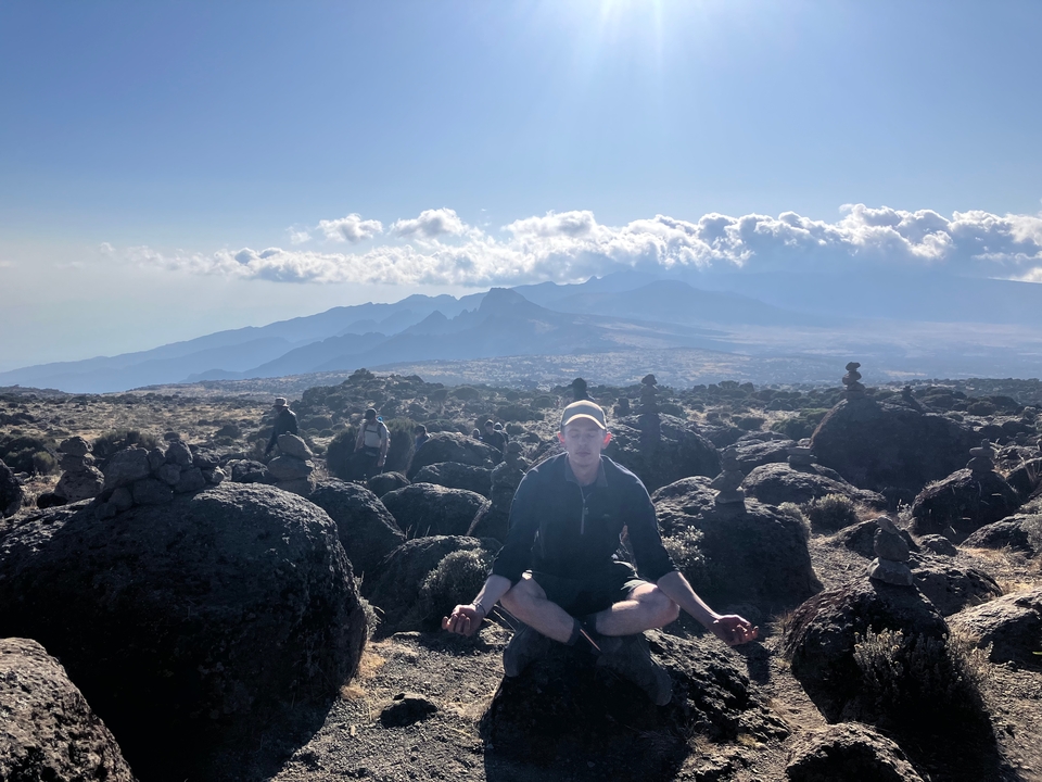 Personne qui médite parmi les rochers avec une vue panoramique sur les montagnes.