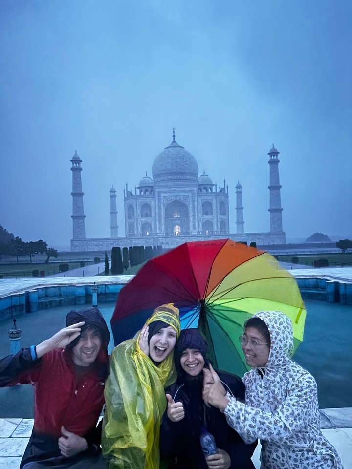 Des personnes tenant un parapluie coloré devant le Taj Mahal.