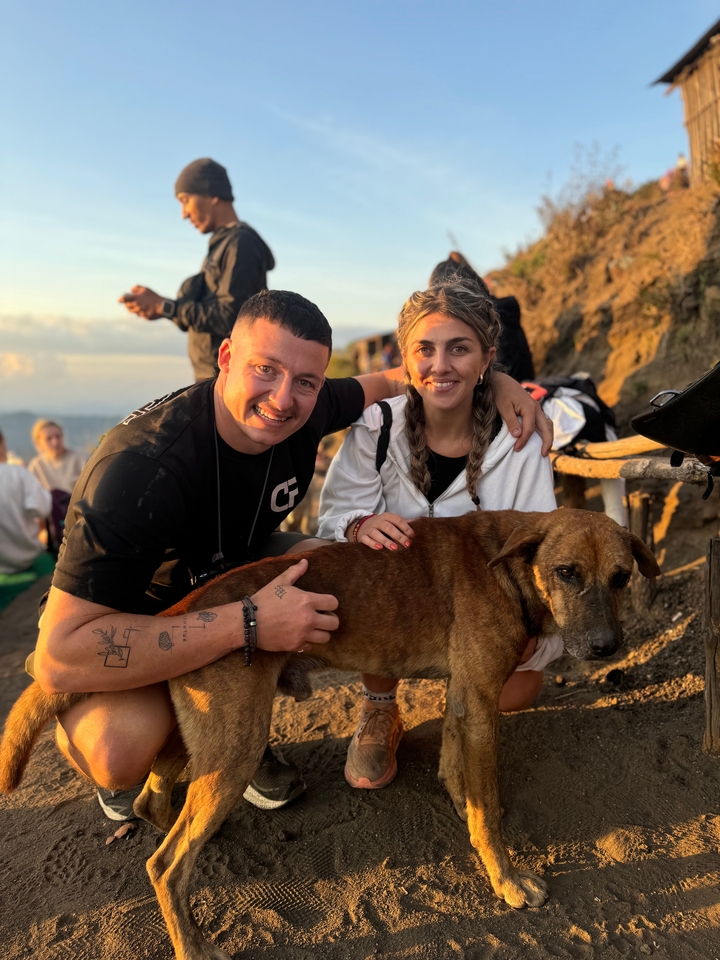 Un couple posant avec un chien dans un cadre extérieur.