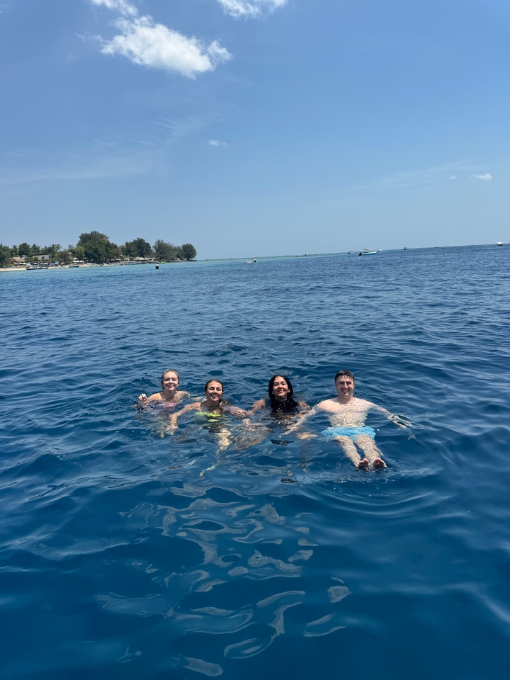 Des gens qui se détendent dans la mer près d'une île tropicale.