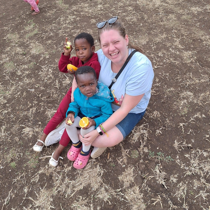 Femme avec deux enfants assise par terre.
