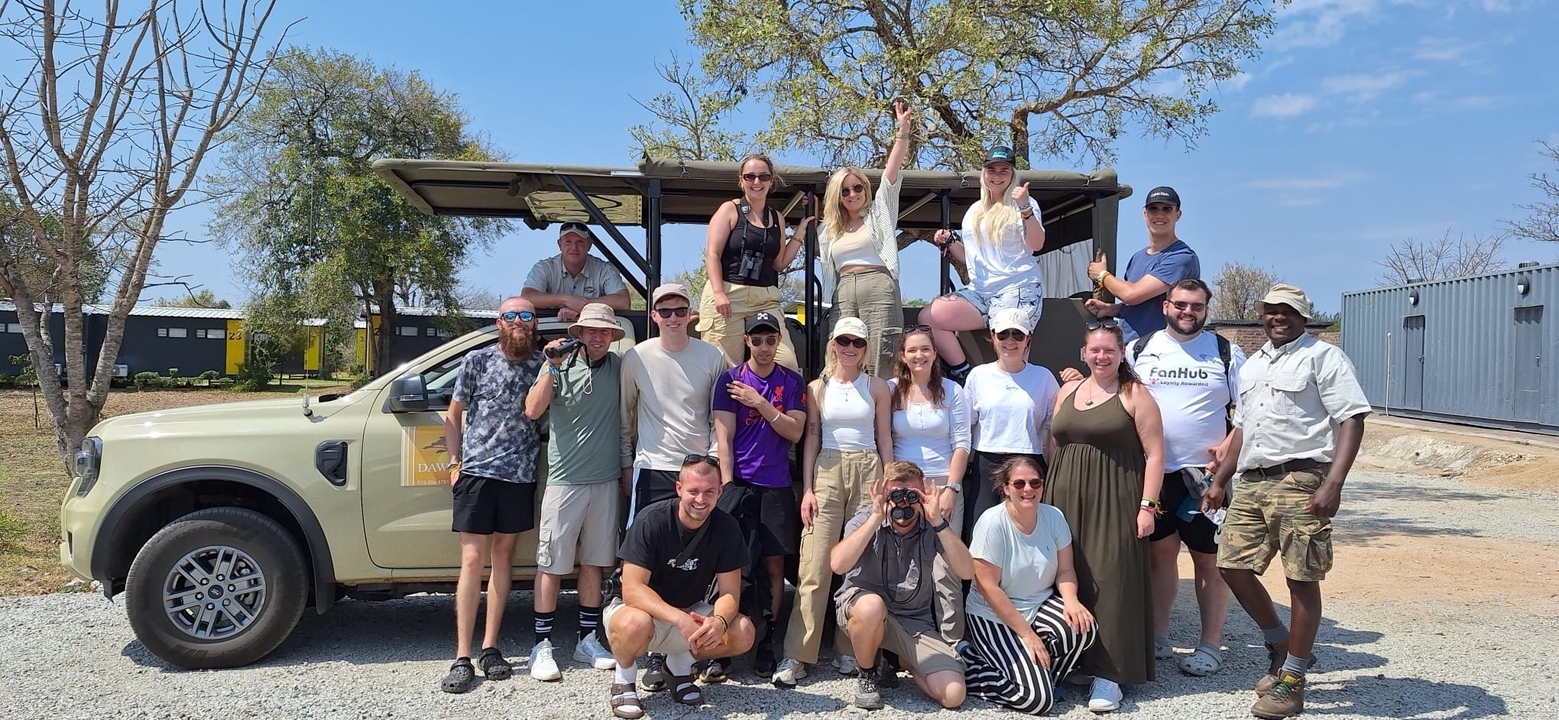 Groupe de personnes posant devant un véhicule de safari.