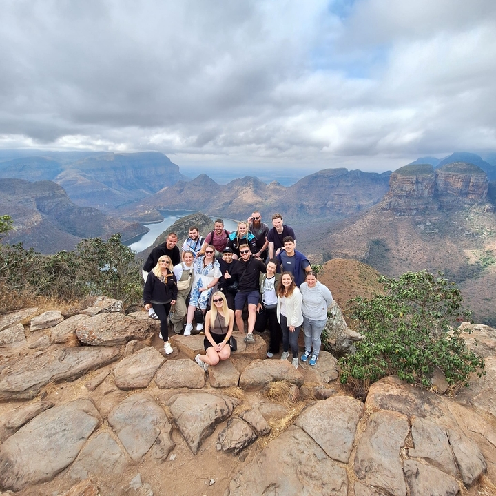 Groupe de personnes posant à un point de vue surplombant les montagnes.