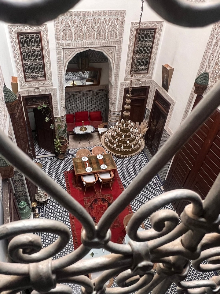 Vue aérienne d'un intérieur marocain traditionnel avec une table dressée pour un repas.