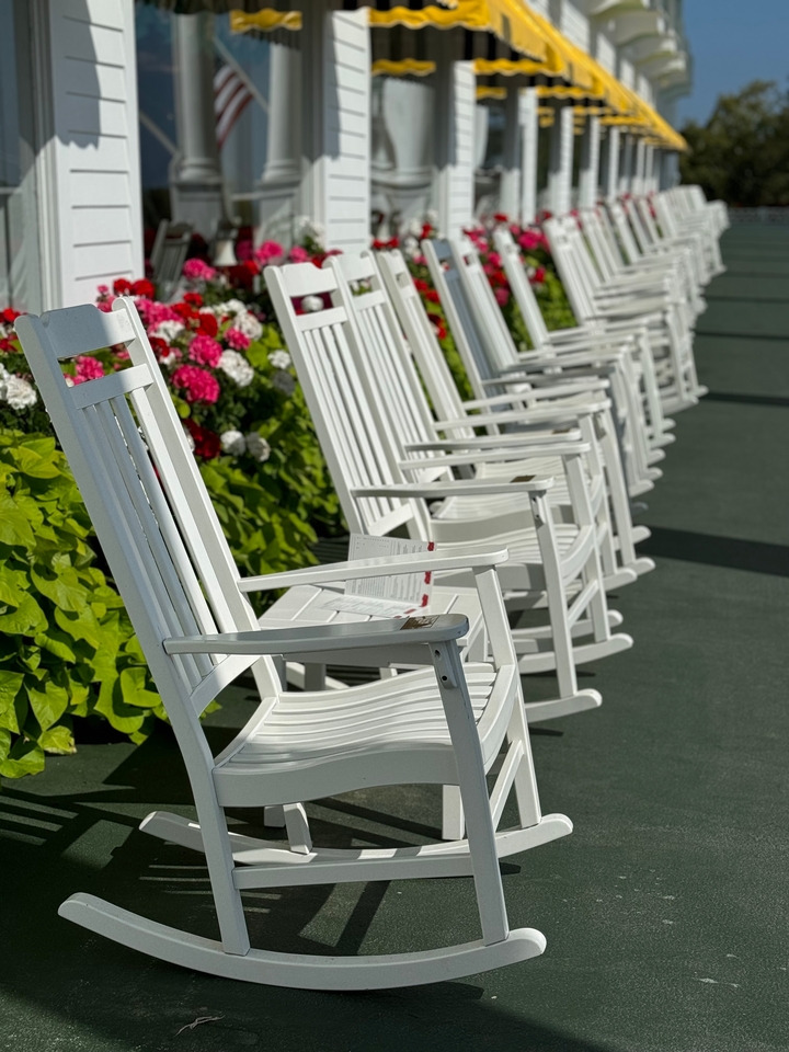 Rangée de chaises berçantes blanches sur une véranda.