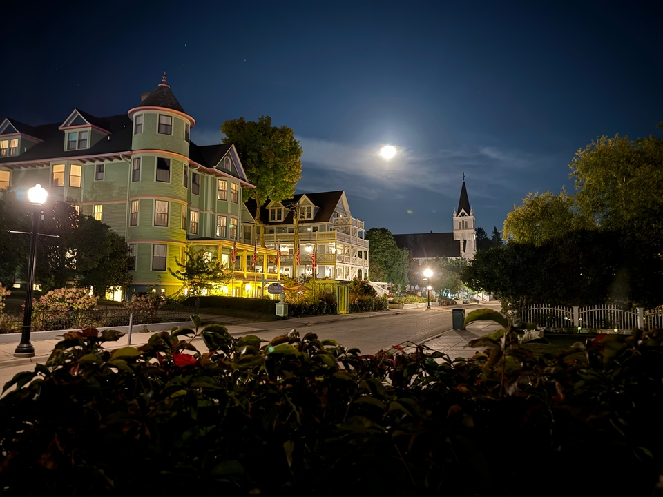 Bâtiments de style victorien illuminés la nuit sous une pleine lune.