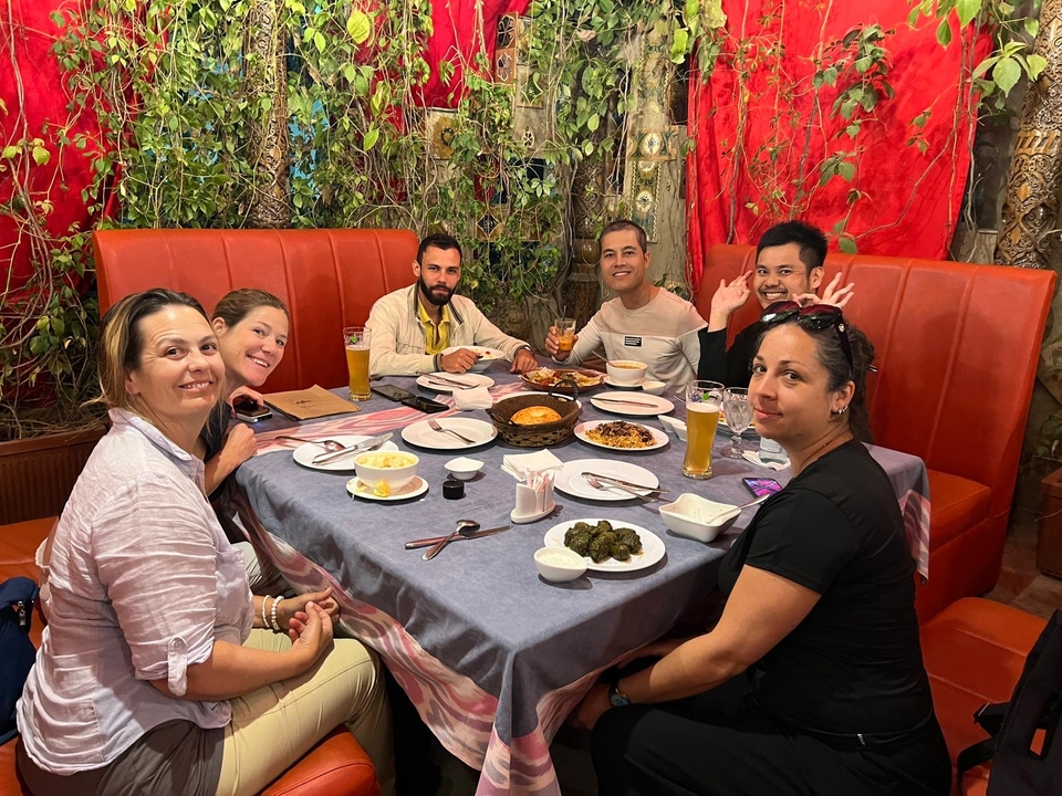 Grupo de personas cenando en una mesa con varios platos.