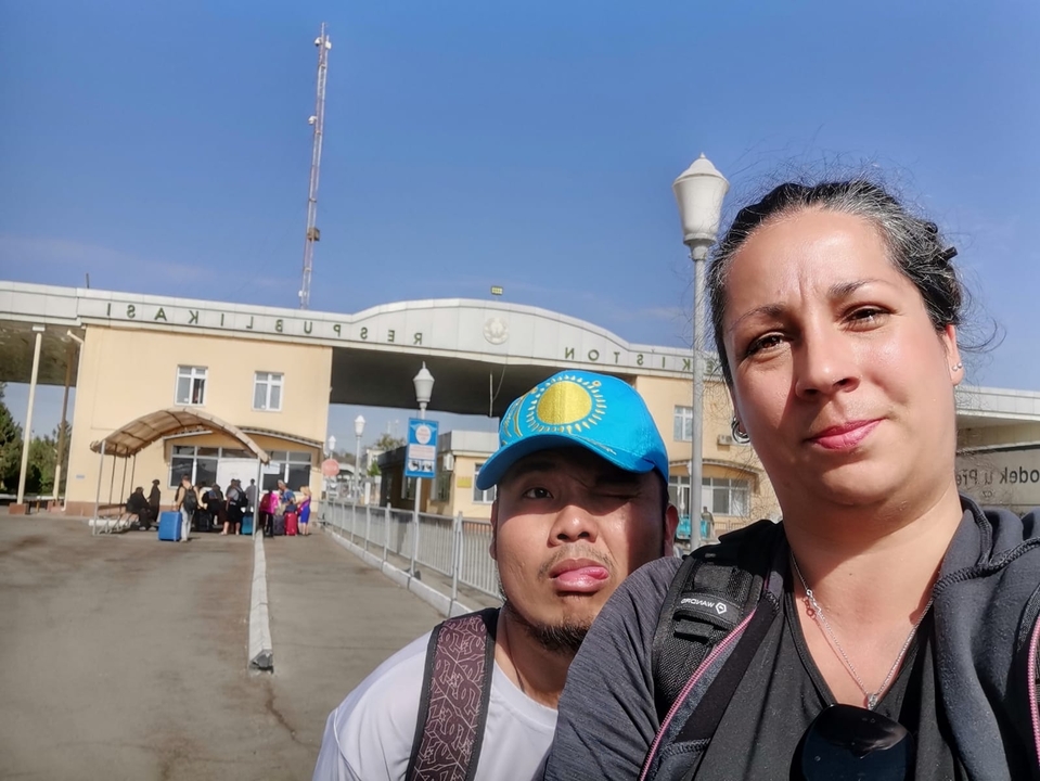 Dos personas posando frente a una puerta fronteriza.