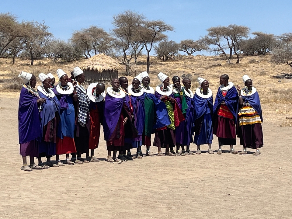Groupe de personnes en tenue traditionnelle debout ensemble à l'extérieur.