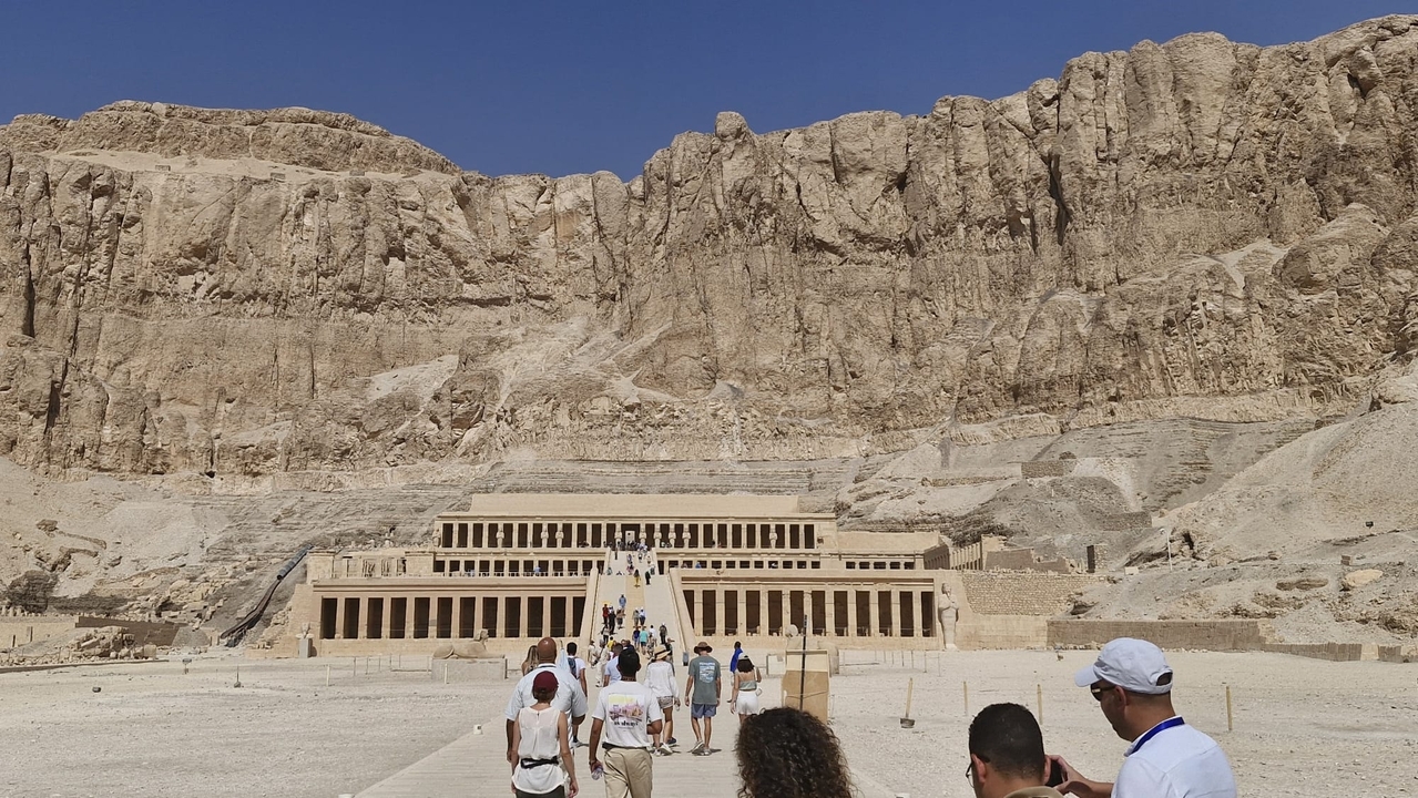 Des visiteurs marchant vers un temple ancien sculpté dans une falaise.