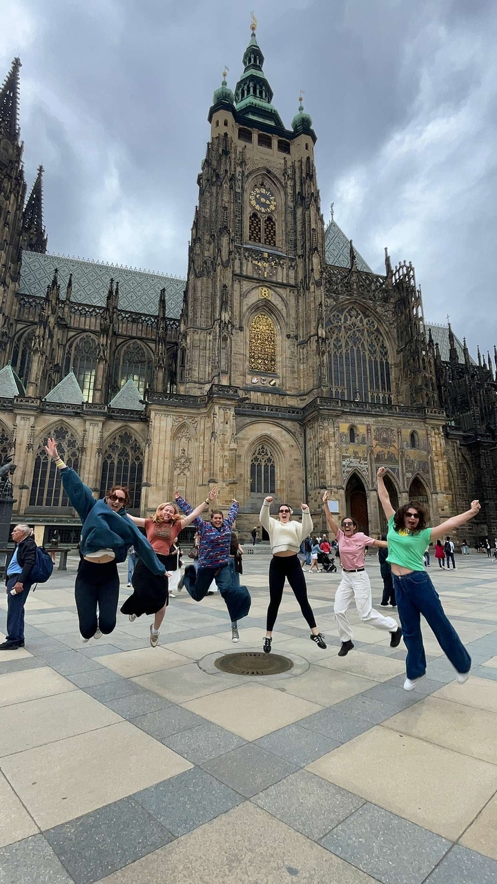 Groupe de personnes sautant devant une grande cathédrale.