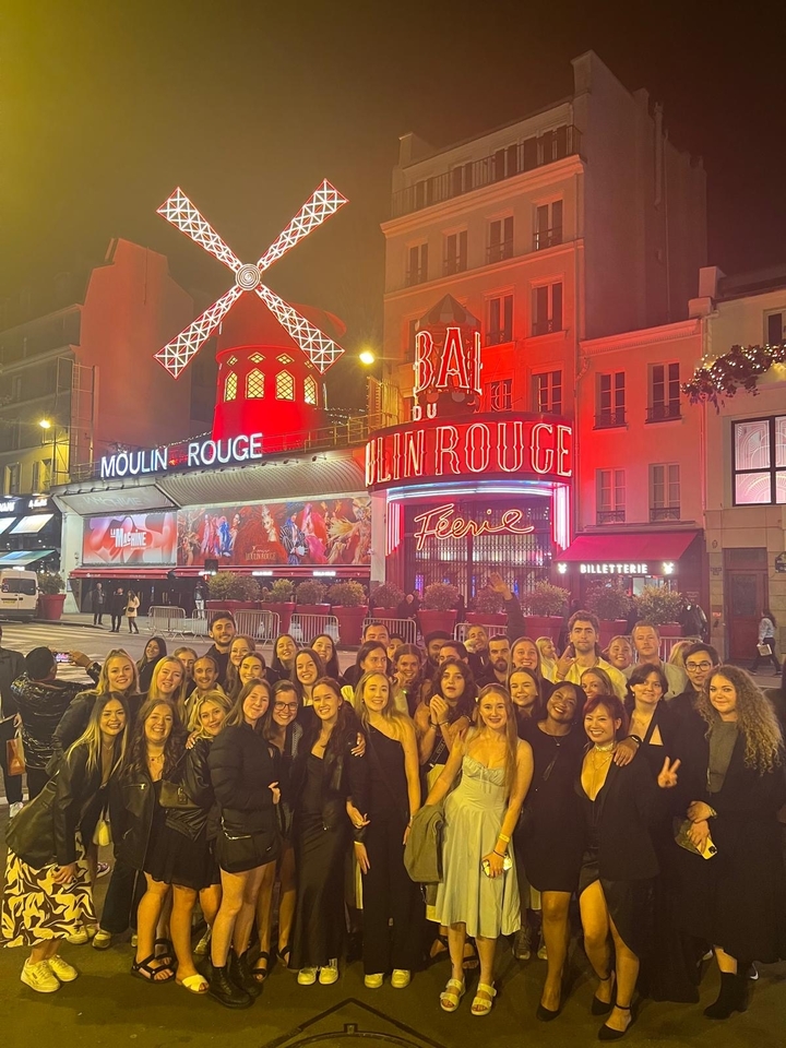 Photo de groupe devant le Moulin Rouge illuminé.