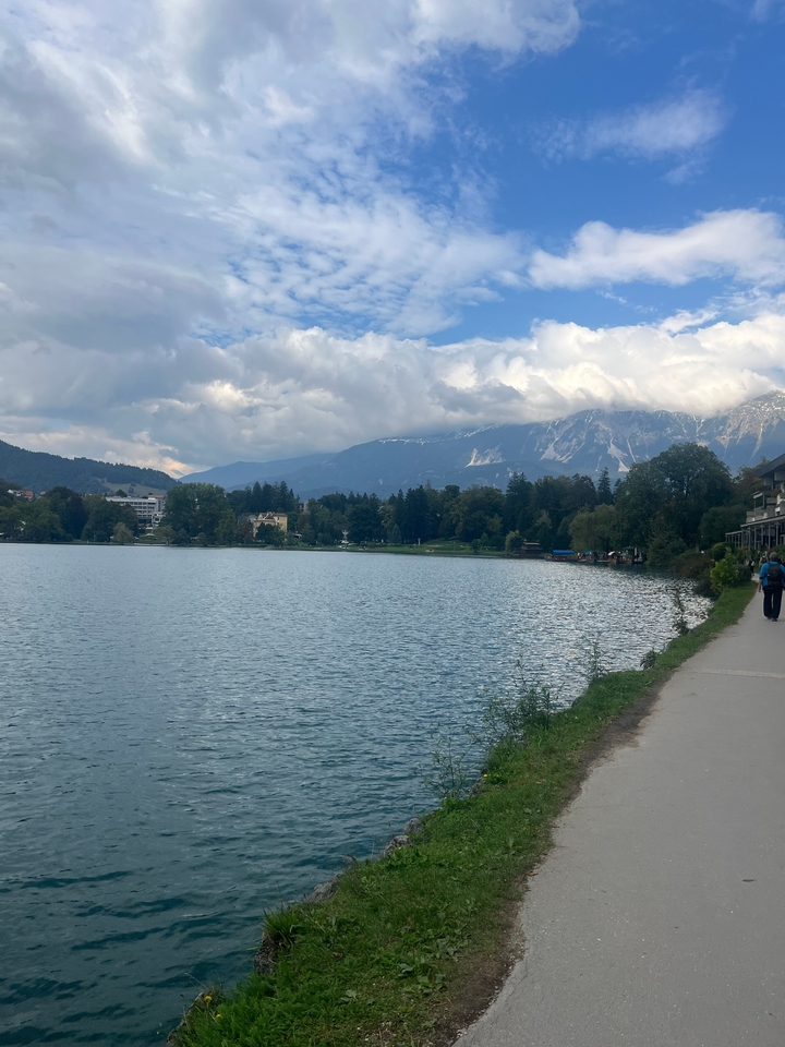 Lac serein avec des montagnes lointaines sous un ciel nuageux.
