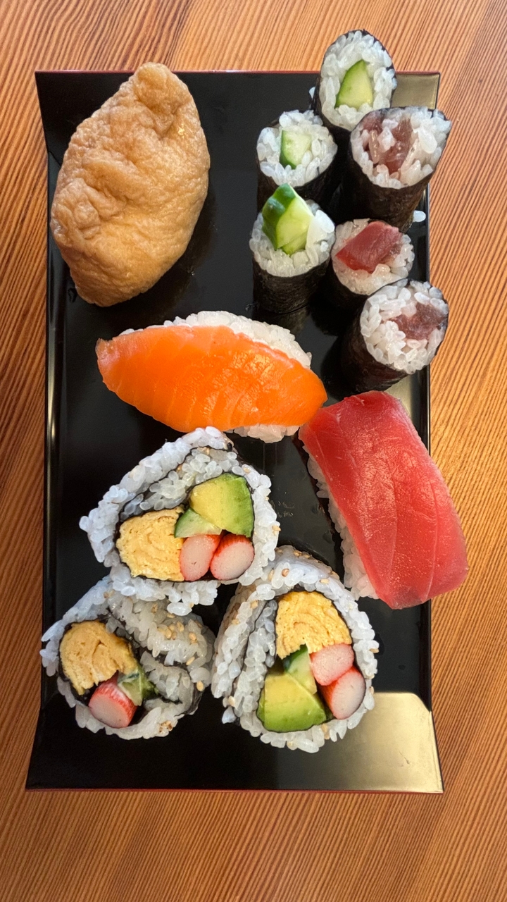 Pièces de sushi assorties sur une assiette noire.