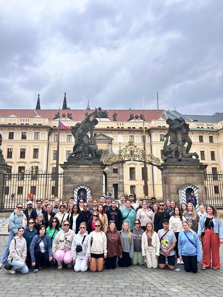 Groupe de personnes posant devant un grand bâtiment historique.
