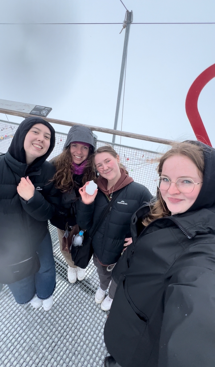 Groupe de personnes posant avec de la neige dans une région montagneuse.