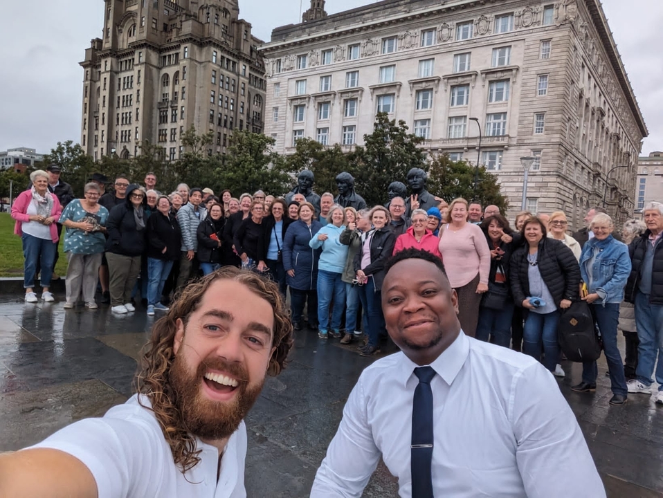Des gens qui posent devant des statues de pierre sur une place de ville.