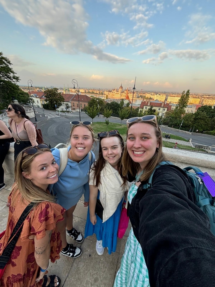 Groupe de femmes avec un paysage urbain en arrière-plan incluant un bâtiment du parlement.