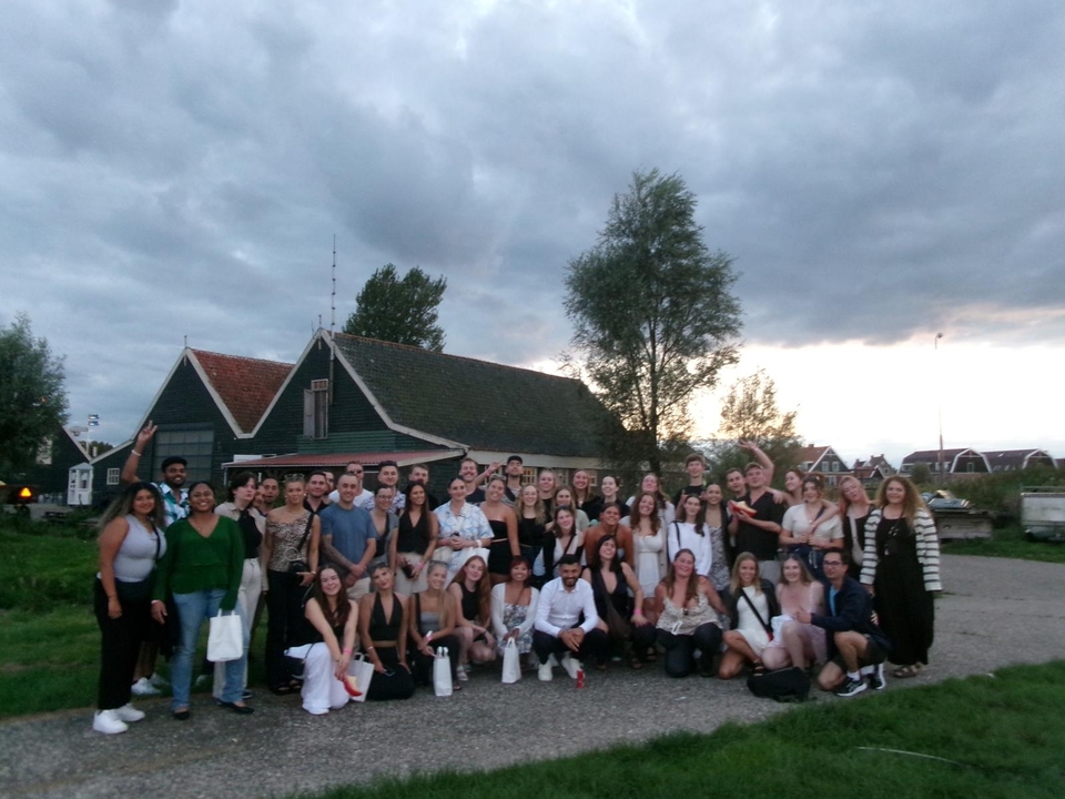 Grande photo de groupe prise en extérieur avec des maisons traditionnelles hollandaises.