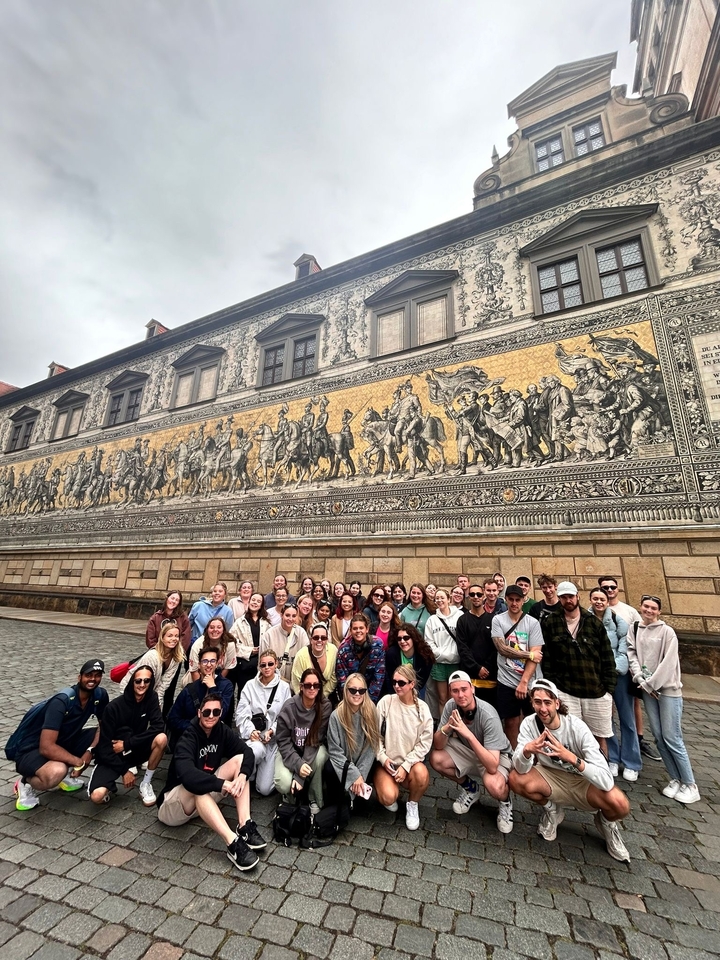 Groupe profitant d'une fresque murale représentant des chevaux et des chevaliers en plein air.