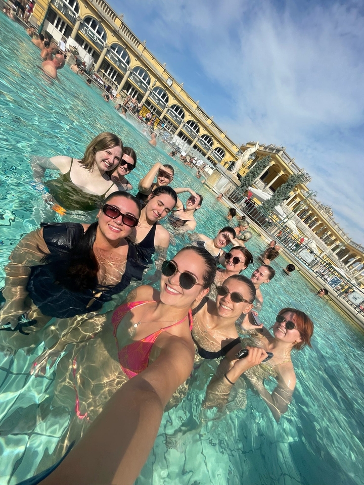 Groupe de personnes profitant d'un bain thermal avec un arrière-plan architectural.