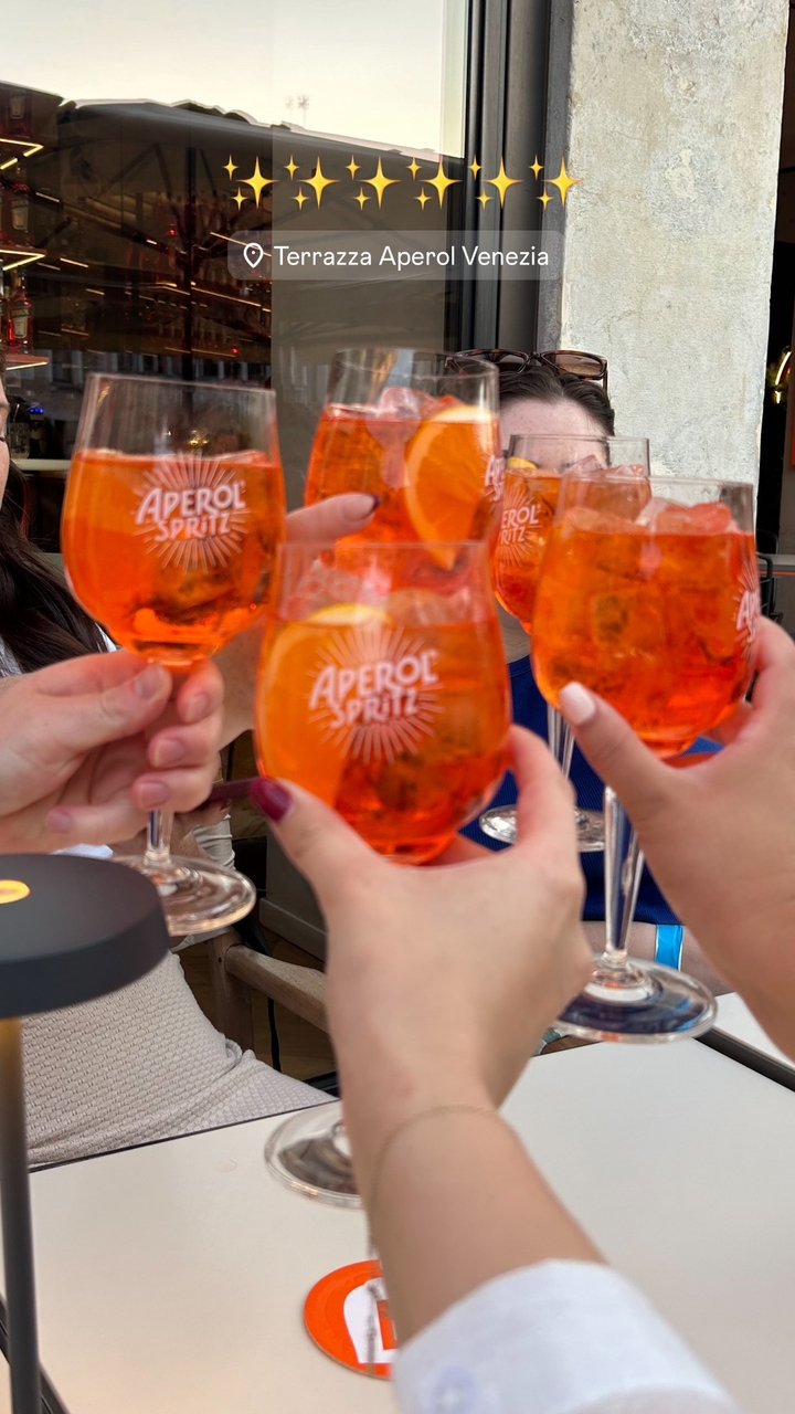 Gros plan sur des verres d'Aperol Spritz portés en toast.